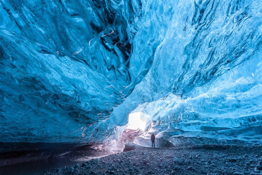 man standing inside massive glacier