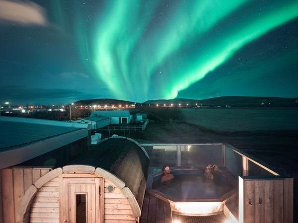 hot tub on patio of hostel with northern lights over head