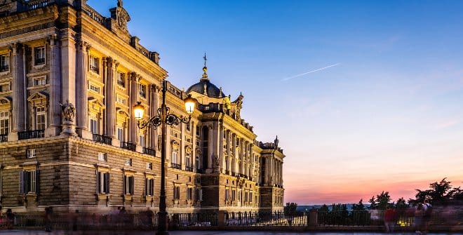 A beautiful palace at sunset with the street lamps just turning on. 