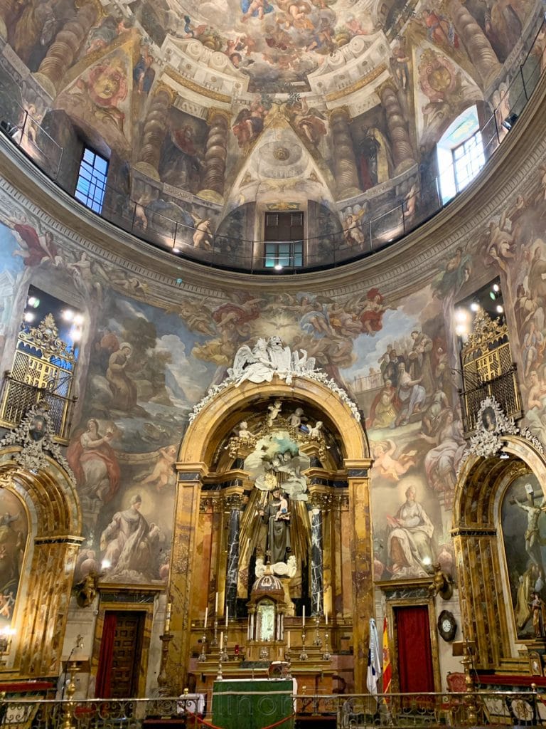 Ornate interior of the Church of San Antonio de los Alemanes in Madrid, Spain, with frescoed dome and gilded altar.