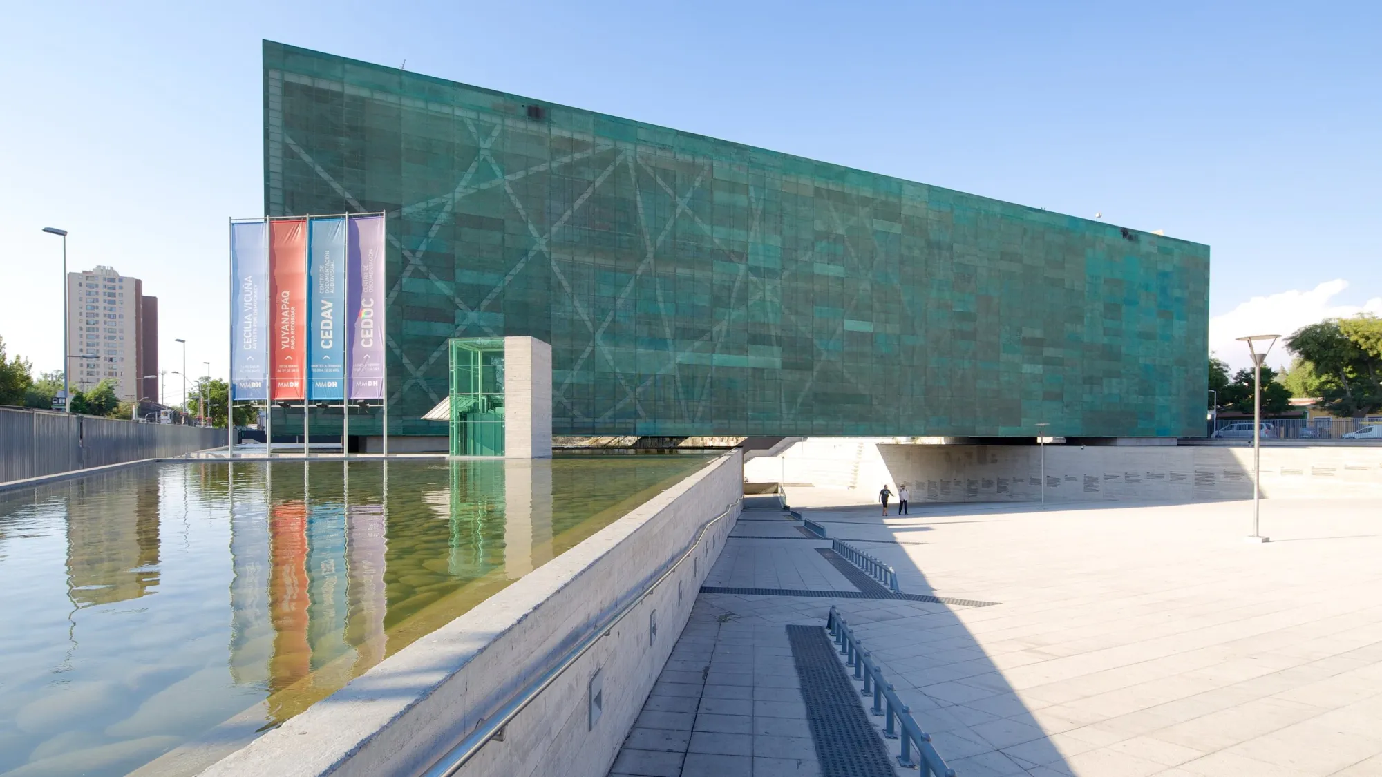 Exterior of the Museum of Memory and Human Rights in Santiago, Chile, featuring a modern green glass facade and black-and-white portraits of victims.