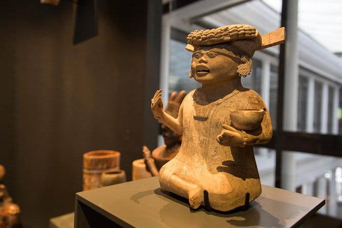 A statue of a small person sitting on display inside of the Chilean Museum of Pre-Columbian Art