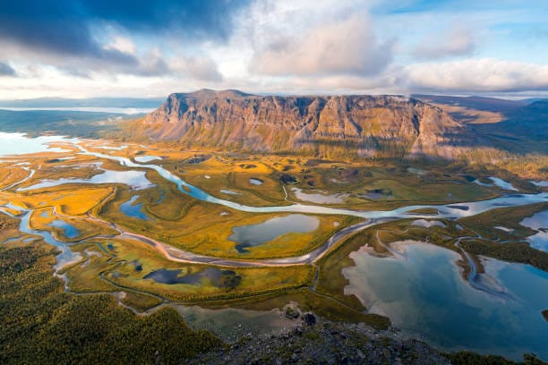 Many small bodies of water near a large flat mountain plateau at Sarek National Park.