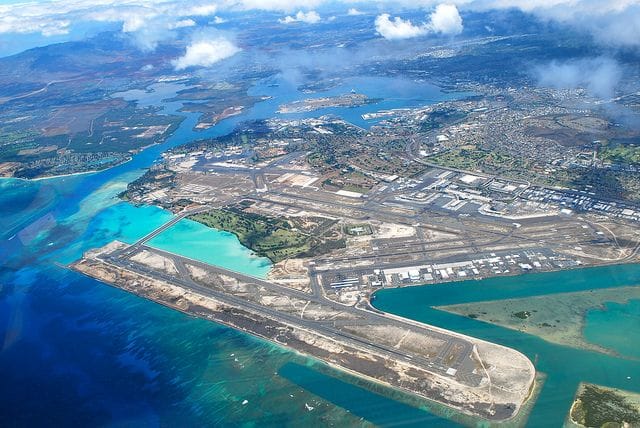 Ariel view of Honolulu Airport showing the runways near pretty blue waters.