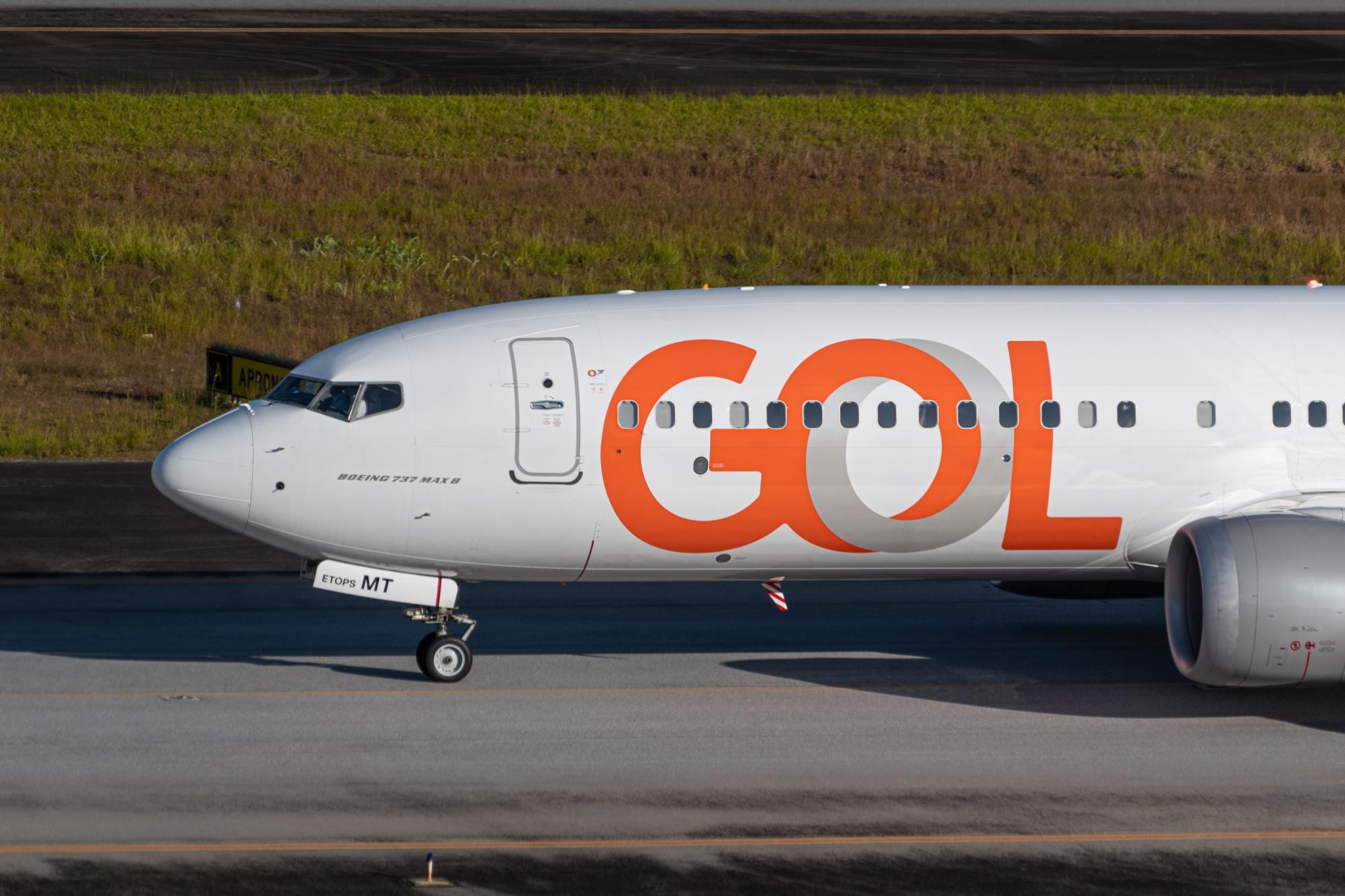 GOL Boeing 737 MAX 8 parked on the airport runway with large orange logo on fuselage.