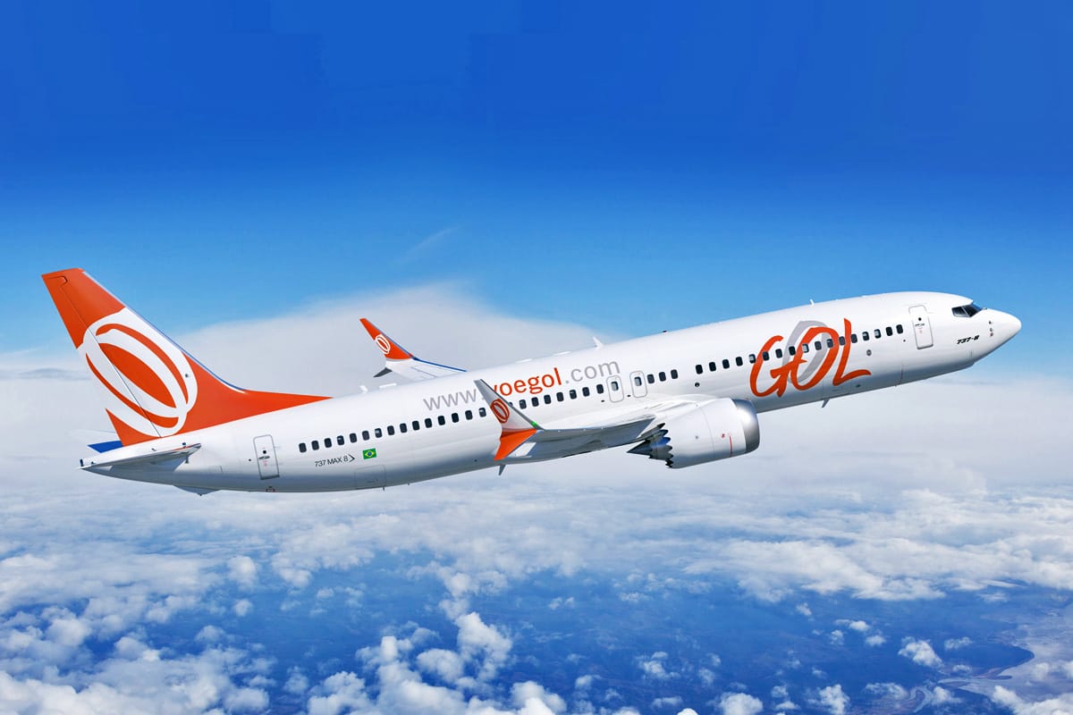 GOL Airlines aircraft cruising above the clouds with a deep blue sky in the background, featuring white fuselage and orange logo.