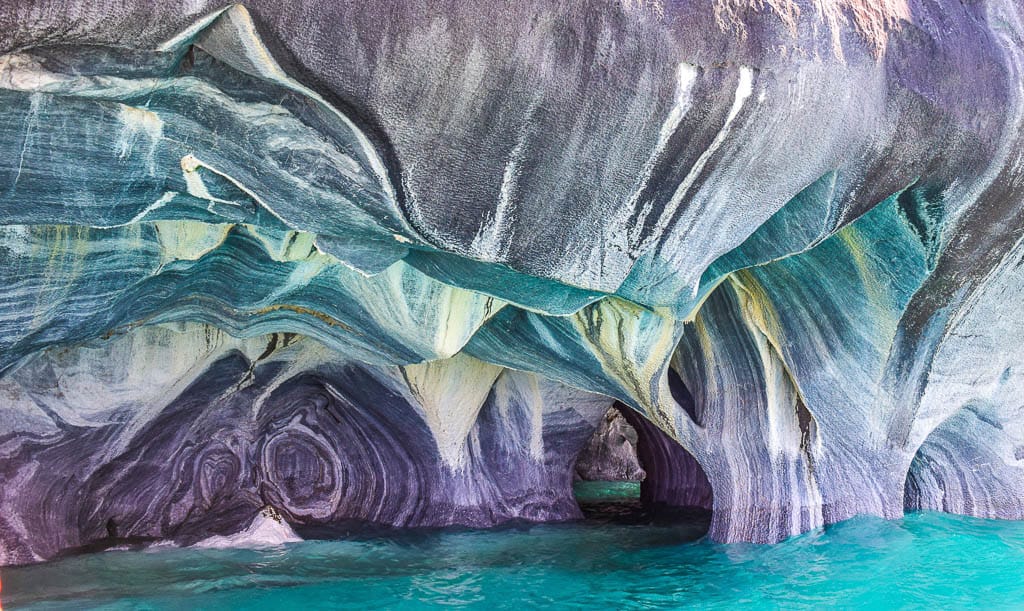 Marble Caves in Chile with swirling blue, white, and gray rock formations above clear turquoise water at General Carrera Lake.
