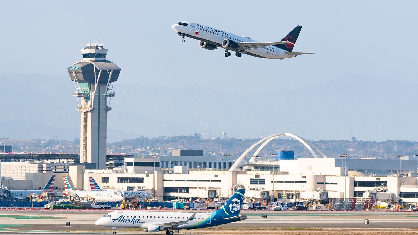 Plane taking off from LAX Los Angeles Airport with the controlling tower in the background.