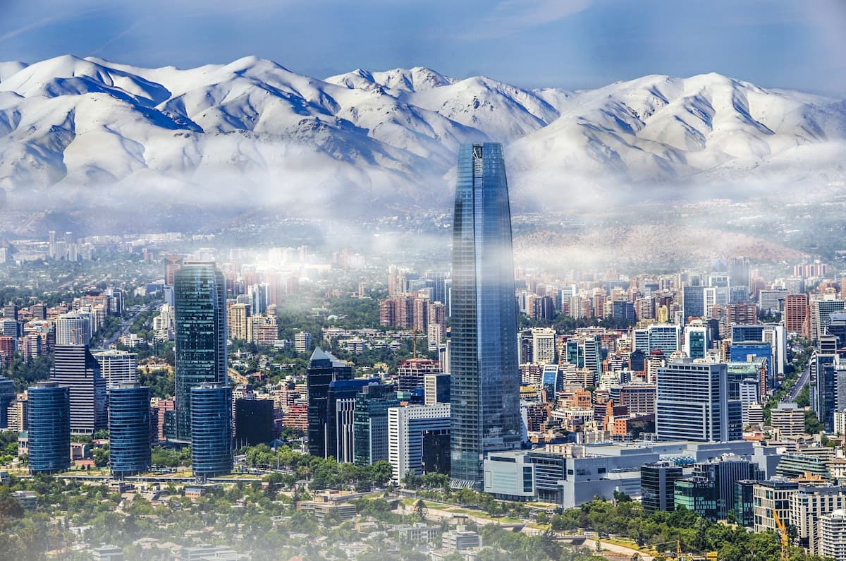 Modern skyline of Santiago, Chile, with the Costanera Center skyscraper and snow-capped Andes Mountains in the background.