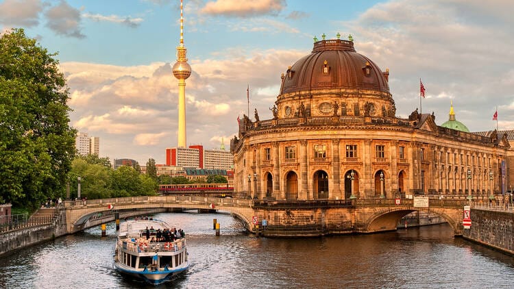 River cruise boat passes Berlin’s Bode Museum with the iconic TV Tower in the background.