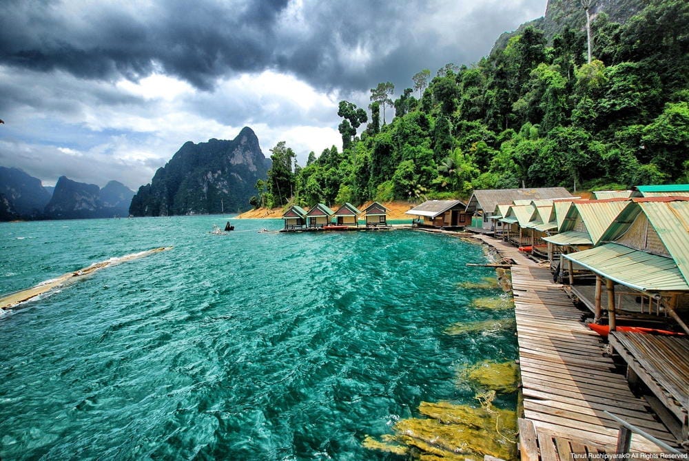 Floating cabins line the emerald waters of Cheow Lan Lake beneath lush limestone cliffs.