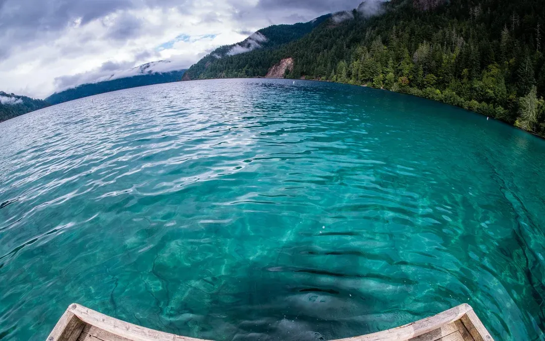 Crystal clear waters of Lake Crescent framed by forested peaks and dramatic skies.