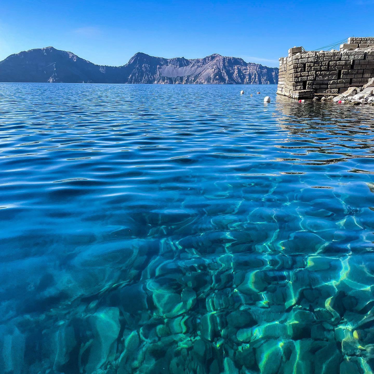Clear, deep blue water of Crater Lake reflecting Oregon’s volcanic rim on a sunny day.