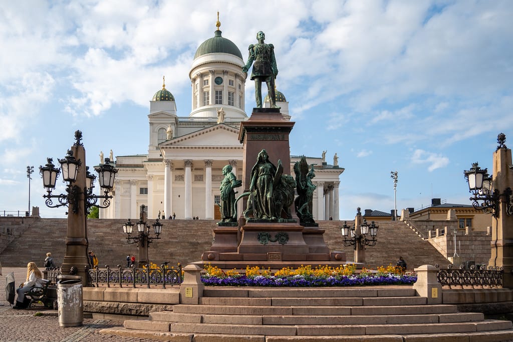 Monument of Alexander II in front of Helsinki Cathedral under a bright blue sky.