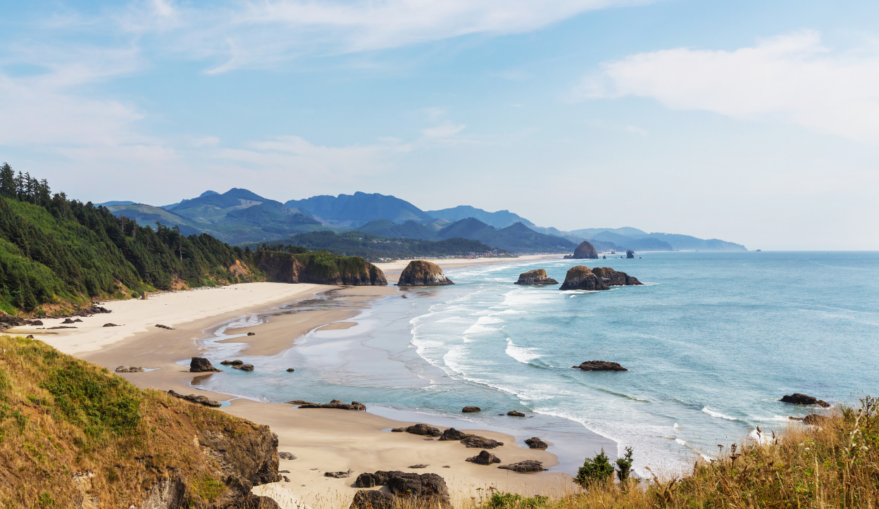 Cannon Beach surrounded by trees and mountains with views of the ocean at Ecola State Park.