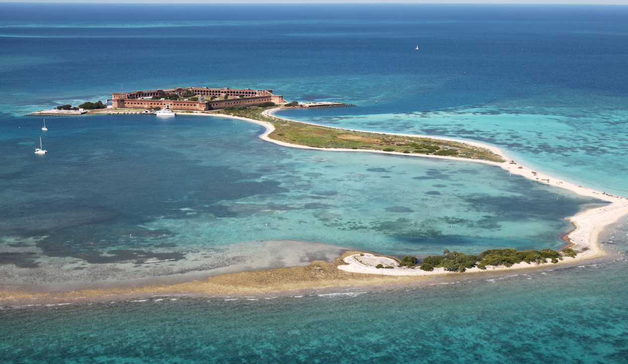 Aerial view of Fort Jefferson on Dry Tortugas island, surrounded by shallow turquoise reefs in the Gulf of Mexico.