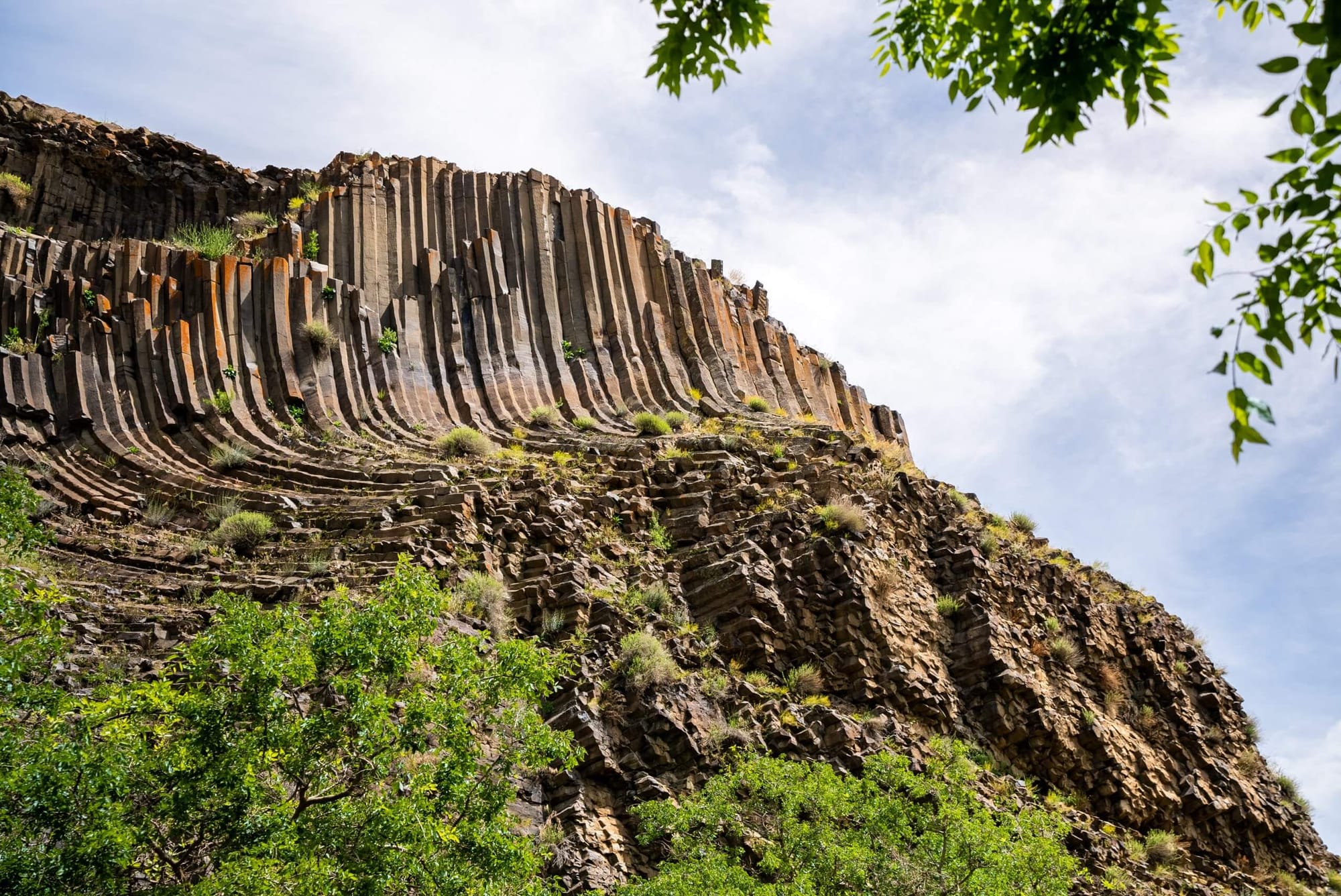Unique columnar basalt rock formations at Hell’s Gate National Park, Kenya, surrounded by green vegetation and framed by trees.