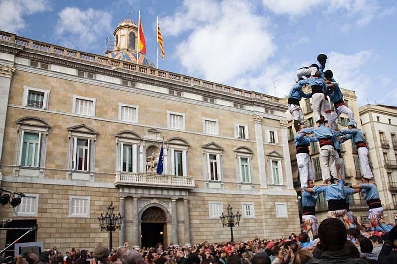 Human tower performance in front of the Government Palace at Plaça Sant Jaume during a cultural festival in Barcelona.