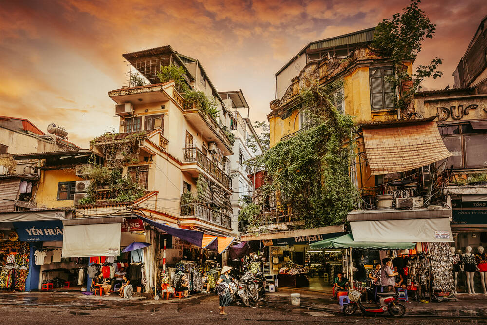 Hanoi buildings with locals selling things on the street on a cloudy day.