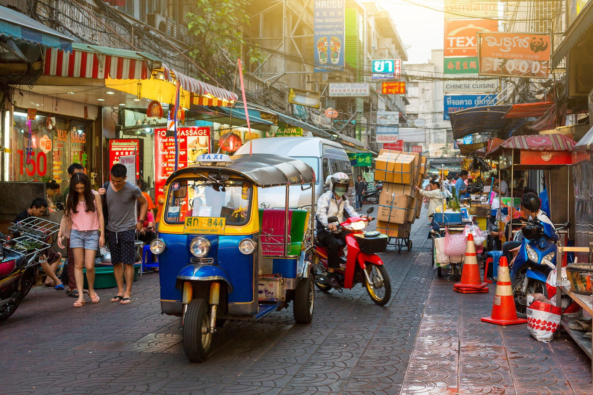 People walking the streets of Bangkok and tuk tuk taxi drivers offering services.