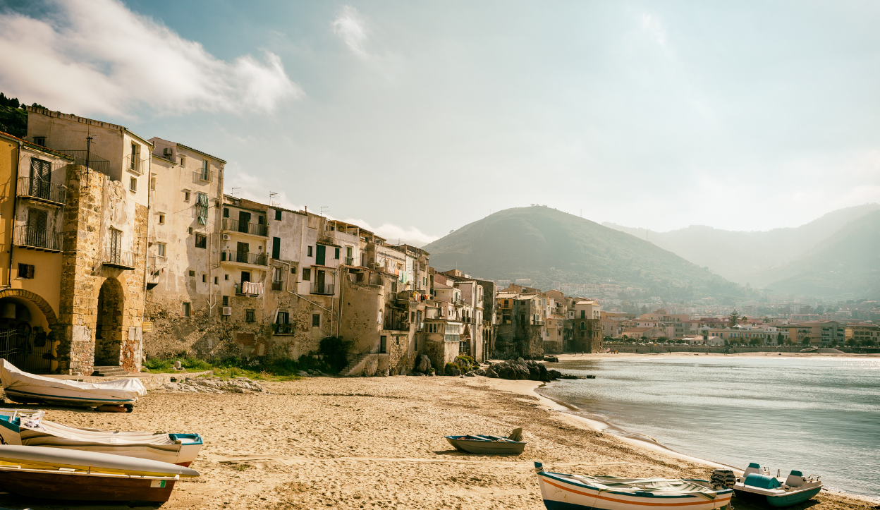 The beach in Cefalù with boats parked on the sand.