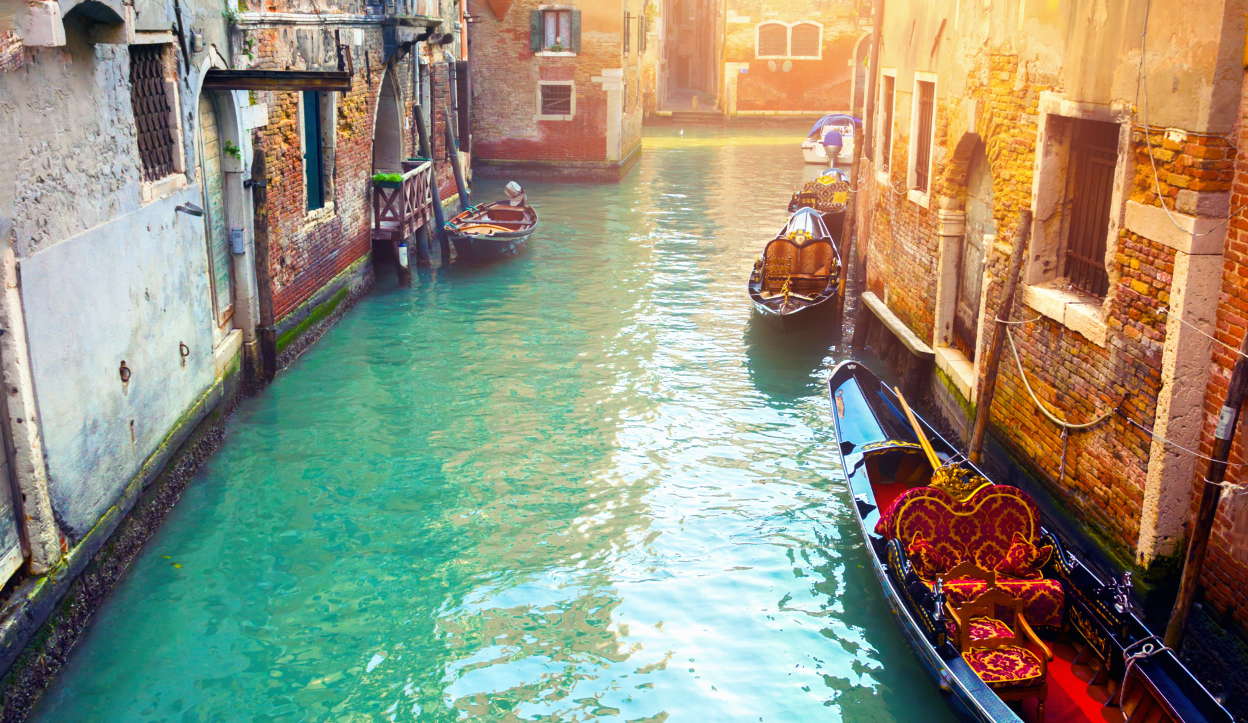 Beautiful canal in Venice, Italy with turquois waters and anchored boats.
