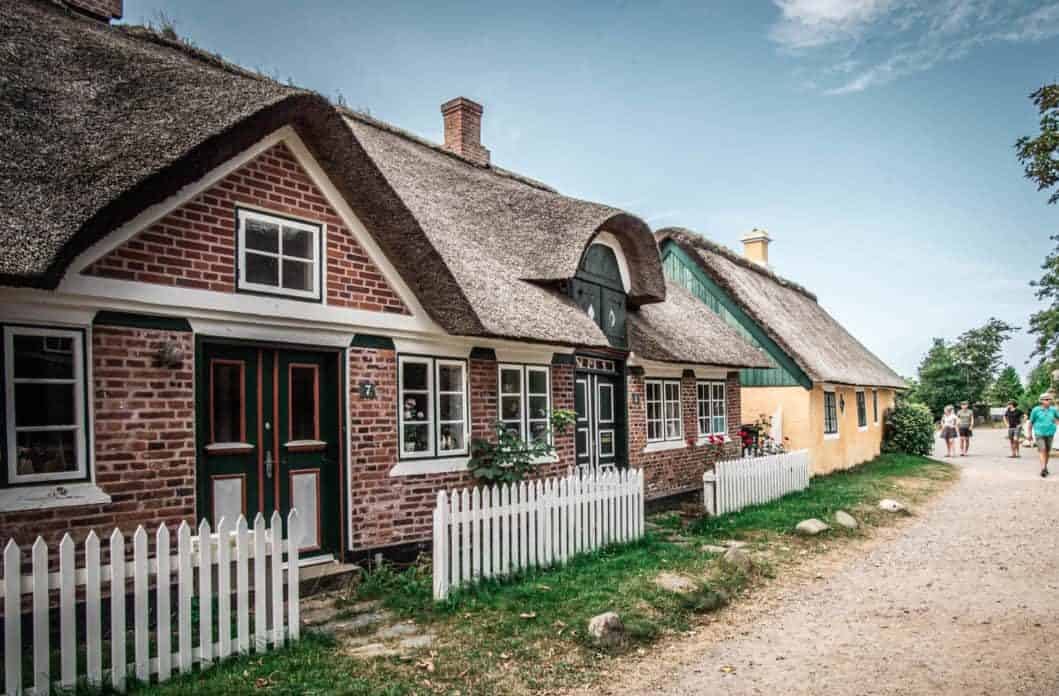 Tourist walking the road looking at houses on Fanø Island, Denmark.
