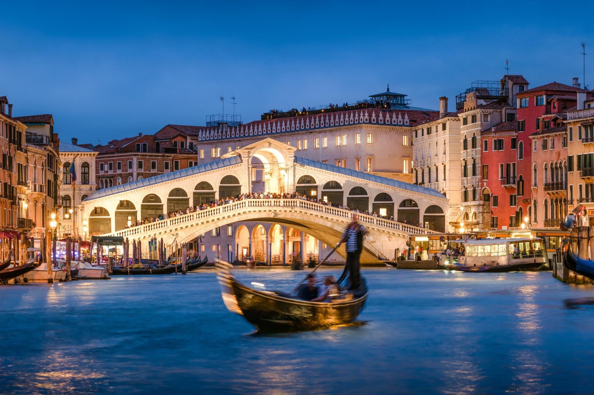 Gondola driver in Venice, Italy at night on the grand canal.
