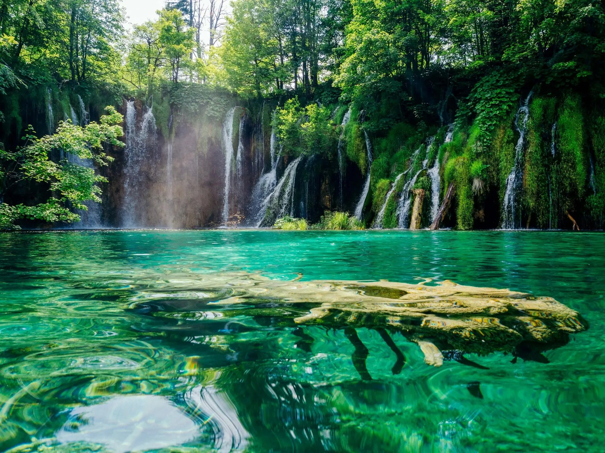 Waterfalls flowing into emerald clear waters in Plitvice Lakes Croatia.