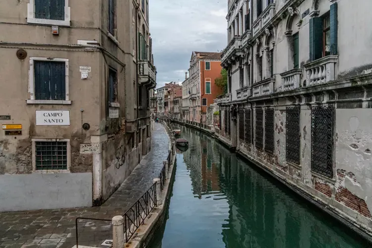 Boats sitting in a small canal between buildings in Santa Croce Neighborhood in Venice, Italy.