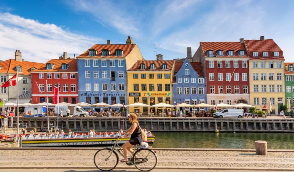 A woman riding a bike on a sunny day in Copenhagen, Denmark.