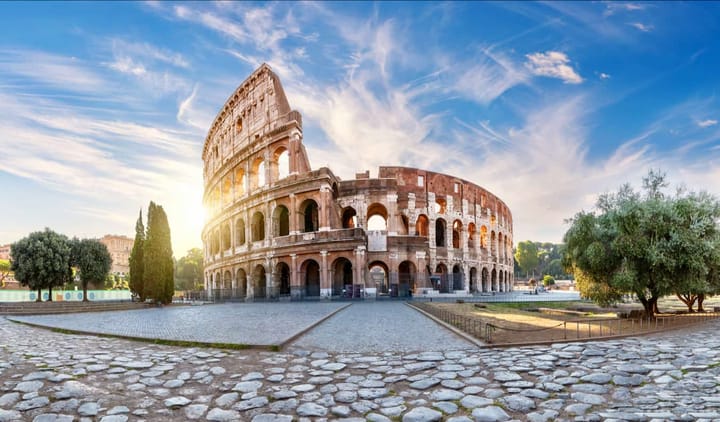 Just after sunrise at the Colosseum In Rome, with the sun peaking out behind the ancient structure. 