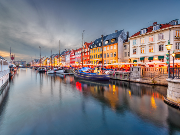 Canal with boats parked along side it and colorful buildings along the road in Demark