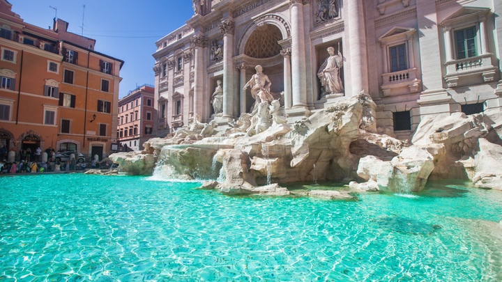 A bright blue pool of clear water a the Trevi Fountain in Rome. 