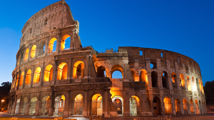 The Colosseum in Rome at Nighttime with clear skies and lights lighting up the Colosseum. 