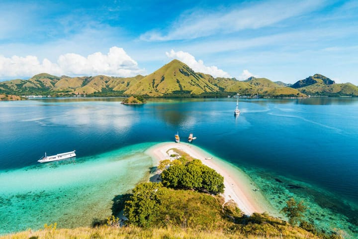 A beach with boats anchored near it's shores at Komodo National Park in Indonesia.