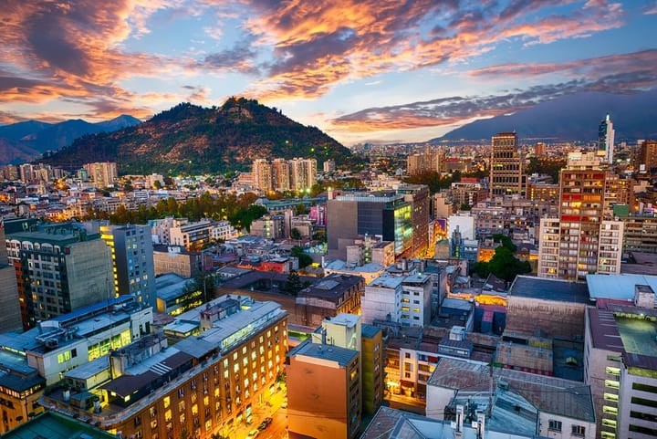 View of Santiago, Chile city skyline just before sunset with a large mountain in the background of the city.