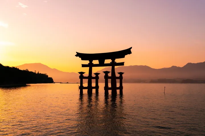 A floating torii gate of Itsukushima Shrine on Miyajima Island, just off the coast of Hiroshima, Japan at sunset.