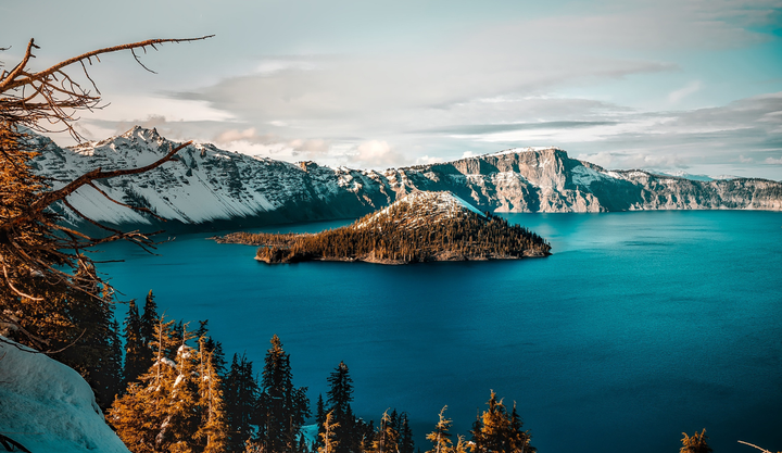 Crater lake covered in snow with mountains with the lake still looking like it's frozen.