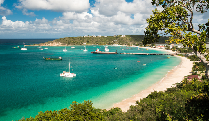 Many sailboats anchored in a bay next to a beach at the Island of Anguilla, in the Caribbean. 