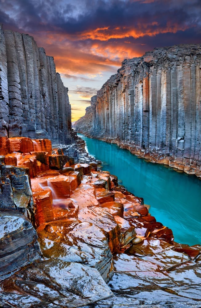 A blue looking river running through a deep and crazy looking canyon in Iceland. 