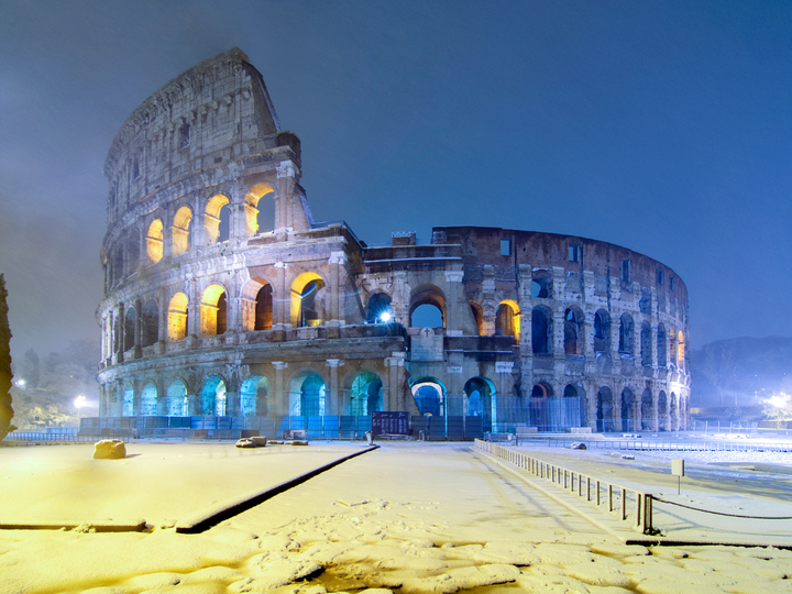 Snow covered colosseum in Rome at night time. 