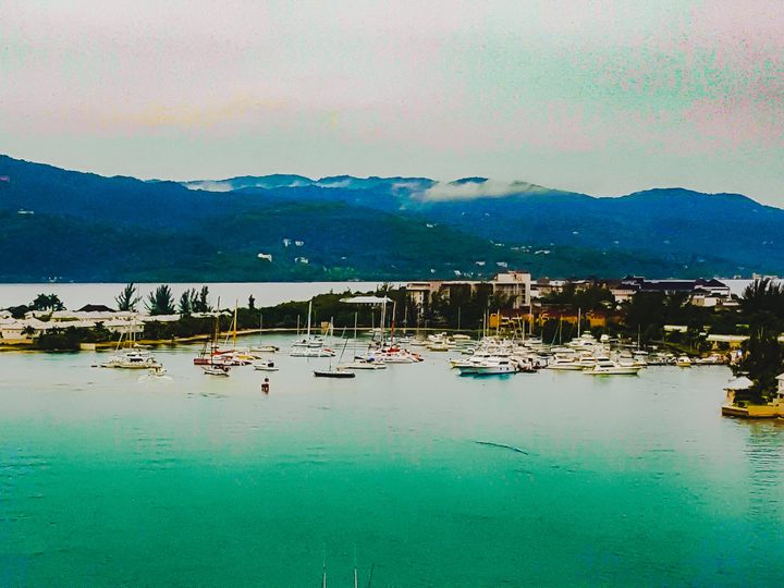 Sailboats parked at a boat marina and mountains in the background in Montego Bay, Jamaica.
