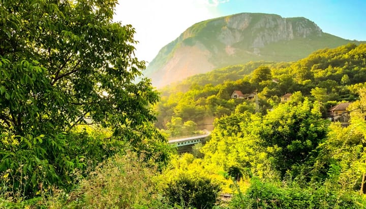 A bridget in rural Serbia in a lush forrest in front of a mounain.