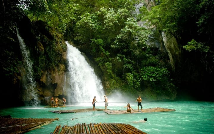 Beautiful waterfall in the Philippines with people floating on bamboo rafts. 
