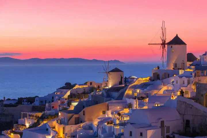 Santorini at Sunset with white buildings and a windmill.