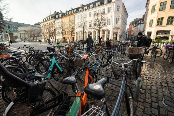 A bunch of Bicycles in Denmark parked on an old cobblestone street. 