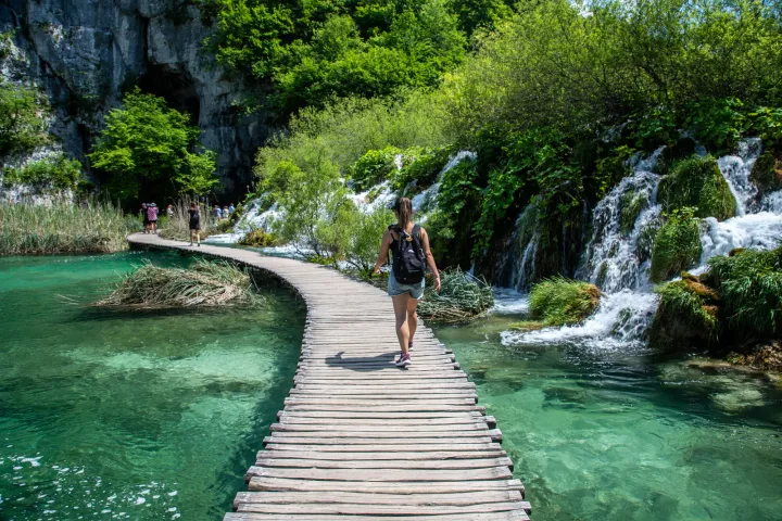 Person walking on a walkway over the water at Plitvice National Park in Croatia.