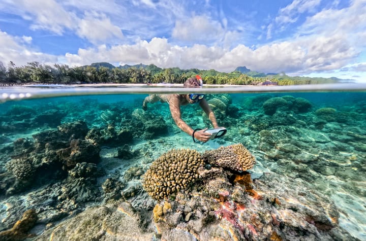 A boy taking underwater photos while snorkeling in the cook islands.
