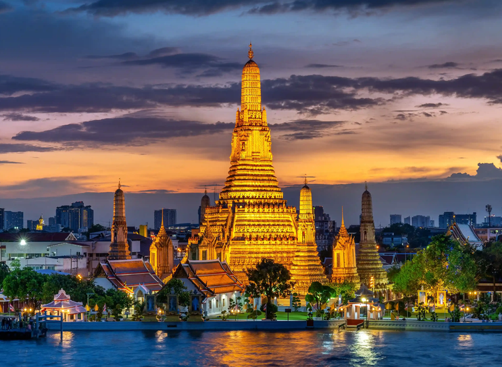 Bangkok temple lit up with bright lights at sunset. 